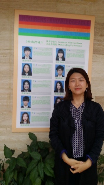 전빛 상해 이화어학원장이 진재중학교 1층 본관 벽면에 부착된 '2016년 우수졸업생' 명부 앞에서 기념촬영을 하고 있다.

