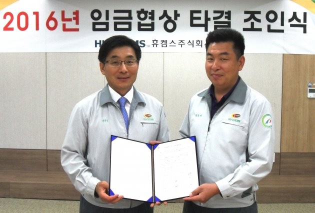 28일 휴켐스 여수공장 대회의실에서 최금성 총괄부사장(왼쪽)과 박종태 노조위원장(오른쪽)이 올해 임금협상 타결합의서에 사인한 후 기념촬영을 하고 있다. 사진=휴켐스 제공
