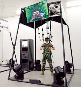 옵티머스시스템이 개발한 가상낙하 로봇 시뮬레이터에서 실험자가 HMD(헤드마운티드디스플레이)를 착용하고 가상낙하 훈련을 하고 있다. 대구시 제공
