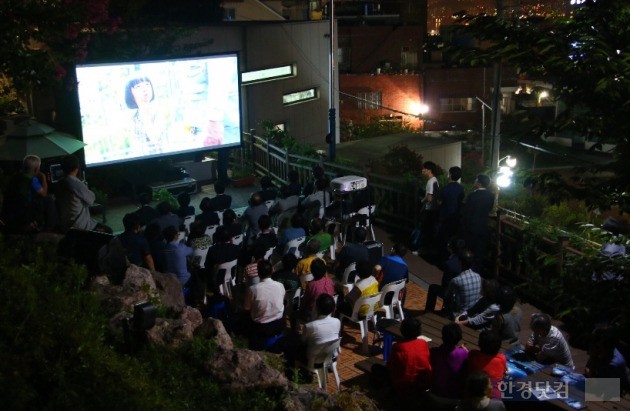 르노삼성자동차가 지난달 15일부터 후원하는 '옥상달빛극장'에 지역 주민들이 모여들어 영화를 감상하고 있다. (사진=르노삼성 제공)