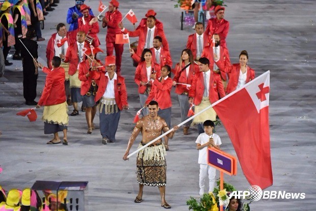 ) 5일(현지시간) 브라질 리우데자네이루의 마라카낭 주경기장에서 열린 2016 리우 올림픽 개막식 행사 중 통가 국가대표 선수단의 기수 피타 니콜라스 타우파토푸아가 전통의상을 입은 채 국기를 들고 입장하고 있다. 리우데자네이루 AFP