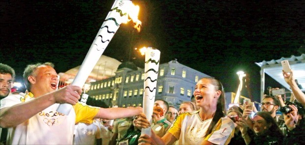 브라질의 세계적인 모델 아드리아나 리마(오른쪽)가 4일(현지시간) 리우데자네이루의 마우아 광장에서 안토니우 페드루 리우데자네이루시 관광국장에게 올림픽 성화를 전달하고 있다. AP연합뉴스 