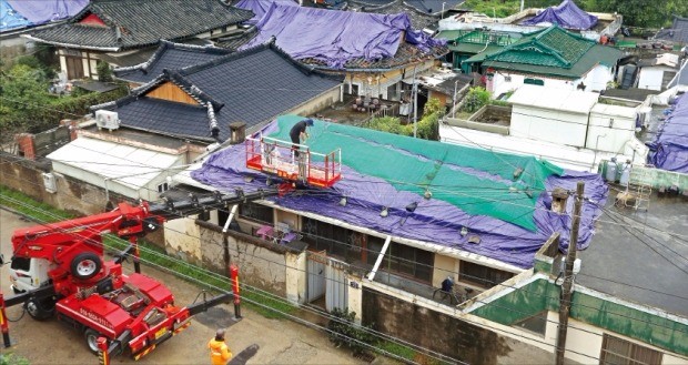 경북 경주시 관계자들이 18일 지진 피해를 입은 사정동 한옥마을 주택 지붕에 천막과 그물을 씌우고 있다. 경주에는 지난 12일 규모 5.8의 강진이 발생한 데 이어 추석 연휴 기간 150㎜가 넘는 비가 쏟아져 추가 피해가 우려되고 있다. 연합뉴스