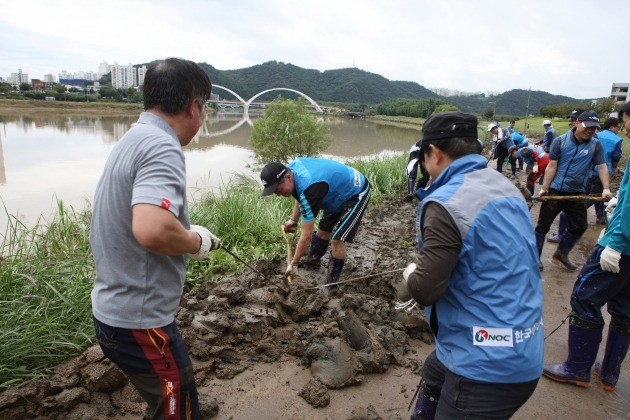 한국석유공사 임직원들이 8일 태화강 강변에 쌓인 토사를 걷어내고 있다.
