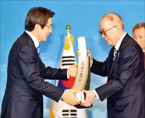 박준 농심 사장(오른쪽)이 황교안 국무총리로부터 1억불 수출의 탑 트로피를 받고 있다.