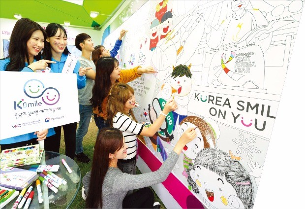 K스마일 엠블럼 모양의 퍼즐을 맞추고 있는 미소국가대표와 시민들. 한국방문위원회 제공      