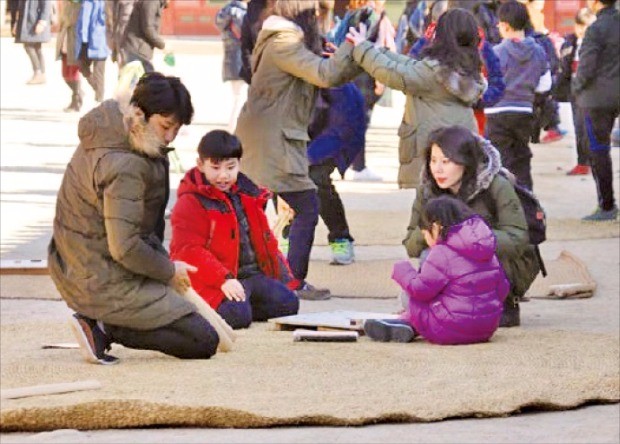 지난해 설 연휴에 덕수궁에서 열린 민속놀이 체험 행사에서 관람객이 윷놀이를 하고 있다.  