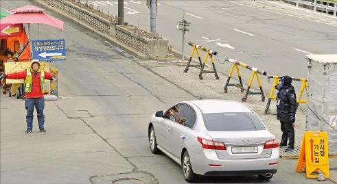 1년째 옛시장과 신시장 상인 간 분쟁이 벌어지고 있는 서울 노량진수산시장에서 7일 양측 주차요원이 서로 다른 방향으로 방문객 차량을 안내하고 있다. 신경훈 기자 khshin@hankyung.com