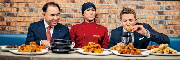 < “한국 치킨 끝내주네요” > 9일(현지시간) 개장한 치킨 프랜차이즈 BBQ의 미국 뉴욕 ‘맨해튼 32번가 직영점’에서 윤홍근 제너시스BBQ 회장(맨 왼쪽)과 셰프가 지켜보는 가운데 폭스뉴스 기자가 치킨을 시식하고 있다. BBQ 제공