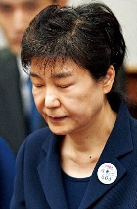 박근혜 전 대통령이 23일 왼쪽 옷깃에 ‘수인번호 503호’ 배지를 달고 눈을 감은 채 재판 시작을 기다리고 있다. 사진공동취재반
