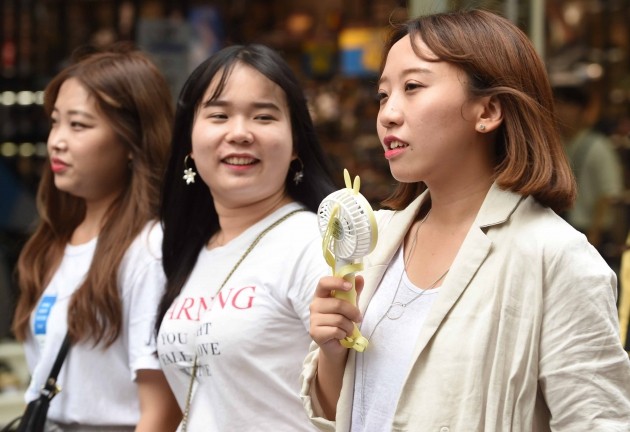 21일 날씨는 전날에 이어 무더위가 계속되겠다. 서울 명동에서 쇼핑객들이 미니 선풍기로 더위를 식히고 있다. 한경DB.