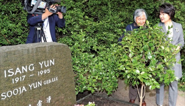 대통령 부인 김정숙 여사와 윤이상 선생의 제자인 박영희 작곡가(왼쪽)가 5일(현지시간) 독일 베를린 가토우 공원묘지에 있는 윤이상 묘소를 찾아 동백나무를 둘러보고 있다. 이 나무는 윤 선생의 고향인 경남 통영에서 공수됐다. 베를린연합뉴스 