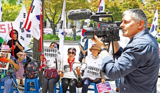 < 외신도 관심 > 한 외신기자가 25일 서울 서초동 서울중앙지방법원 앞에서 이재용 삼성전자 부회장을 석방하라는 피켓을 든 시위대를 촬영하고 있다. 서울중앙지법 형사합의27부 김진동 부장판사는 이 부회장에게 징역 5년을 선고했다.  강은구 기자 egkang@hankyung.com 