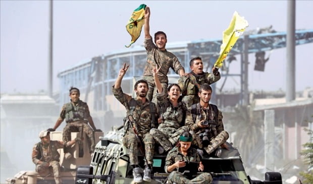 시리아 민주군(SDF)이 17일(현지시간) 이슬람 수니파 극단주의 무장단체 이슬람국가(IS)의 수도 역할을 한 시리아 락까를 3년9개월 만에 탈환했다. SDF는 쿠르드족과 시리아 정부군 등으로 구성된 연합군이다. IS 조직원과 가족 등 약 3000명이 지난 주말 철수해 이날 대규모 지상전은 벌어지지 않았다. 앞으로 락까 통치 주도권을 놓고 시리아 정부와 쿠르드족, 현지 주민 간 갈등이 빚어질 것으로 관측된다. 군용차량에 탑승한 SDF 소속 병사들이 승리의 기쁨을 표시하며 락까에 들어서고 있다.   락까로이터연합뉴스 