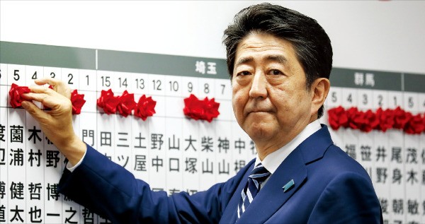 아베 신조 일본 총리가 22일 자민당 당사에서 자민당 소속 중의원(하원의원) 선거 당선자의 이름에 빨간 장미를 달아주고 있다.  /도쿄EPA연합뉴스 