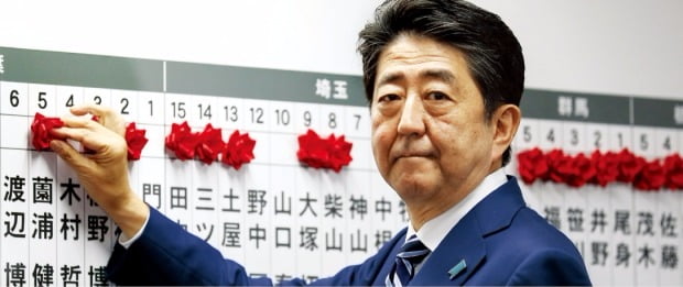 아베 신조 일본 총리가 22일 자민당 당사에서 자민당 소속 중의원(하원의원) 선거 당선자의 이름에 빨간 장미를 달아주고 있다. 도쿄EPA연합뉴스