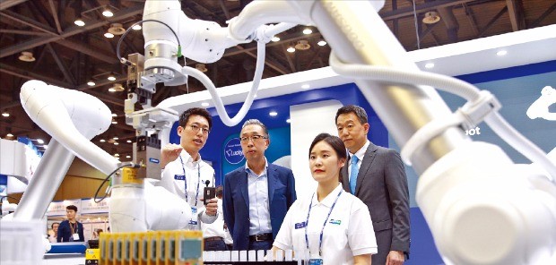 박지원 두산그룹 부회장(왼쪽 두 번째)이 이병서 두산로보틱스 대표(오른쪽)와 함께 ‘2017 로보월드 전시회’에서 두산 협동로봇 시연을 보고 있다.  두산 제공 