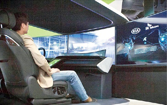 SK텔레콤 직원이 CES 2018 전시장에 설치된 5G 자율주행 콕핏에 앉아 자율주행을 체험하고 있다. SK텔레콤 제공