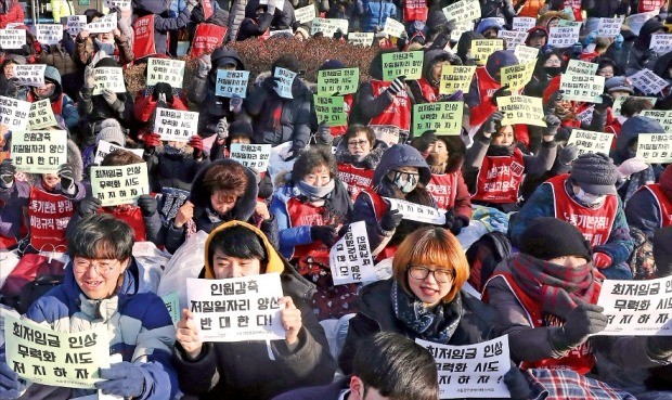 대학 청소·경비직 근로자 등이 11일 서울 광화문 인근에서 ‘최저임금 인상 무력화 시도 저지’ ‘인원 감축, 저질 일자리 양산 반대’ 구호가 적힌 종이 팻말을 들고 시위를 벌이고 있다. 연합뉴스