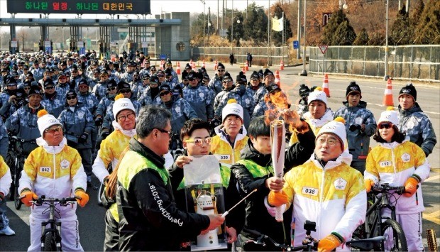 평창동계올림픽 자전거 성화봉송 행사가 19일 최북단 접경지인 경기 파주시 도라산 남북출입사무소 앞에서 열렸다. 첫 봉송 주자인 구자열 LS그룹 회장(앞줄 맨 오른쪽)과 600여 명의 자전거 서포터스들이 출발 전 성화를 바라보고 있다. 파주=김영우 기자 youngwoo@hankyung.com