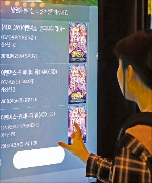 서울의 한 영화관을 찾은 관객이 할리우드 대작 ‘어벤져스: 인피니티 워’의 예매 티켓을 출력하고 있다. 연합뉴스 
