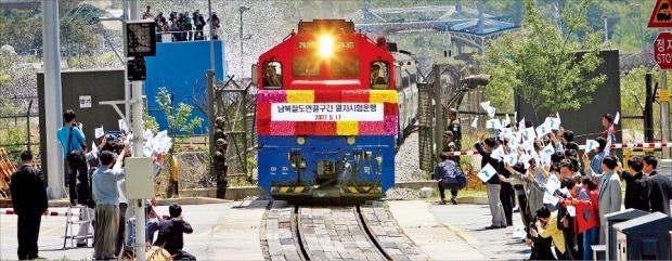 < 11년 前… 경의선 남북 연결구간 시험운행  남북한 정상이 지난 27일 ‘판문점 선언’을 통해 동해선과 경의선 철도 및 도로를 연결하고 현대화하기로 합의함에 따라 남북 카지노 입플협력에 대한 기대가 커지고 있다. 2007년 5월 남북 철도 연결구간에서 시험운행된 경의선 열차가 우리 측 통문을 지나 북측으로 향하는 모습. 한경 DB