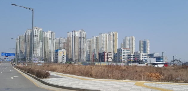 인천 영종하늘도시의 아직 개발되지 않은 부지 뒤편으로 상가건물과 아파트 단지가 들어서 있다. 한경DB