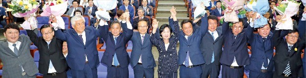 추미애 더불어민주당 대표(가운데)와 6·13 지방선거에서 승리한 당선자들이 14일 국회에서 열린 의원총회에 앞서 손 잡고 꽃다발을 들며 기뻐하고 있다. 연합뉴스