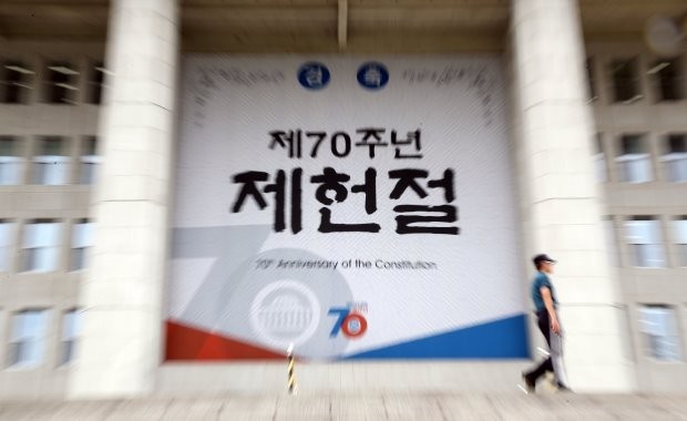 제70주년 제헌절을 일주일 앞둔 지난 11일 국회의사당에 부착된 대형 현수막 앞을 경찰이 지나고 있다. 사진=연합뉴스