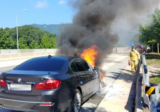 지난 15일 경북 영주시 장수면 중앙고속도로 춘천 방향 영주휴게소 입구에서 BMW 520d 승용차 엔진룸에서 불이 나 소방대원들이 진화에 나서고 있다.  [영주소방서 제공=연합뉴스]