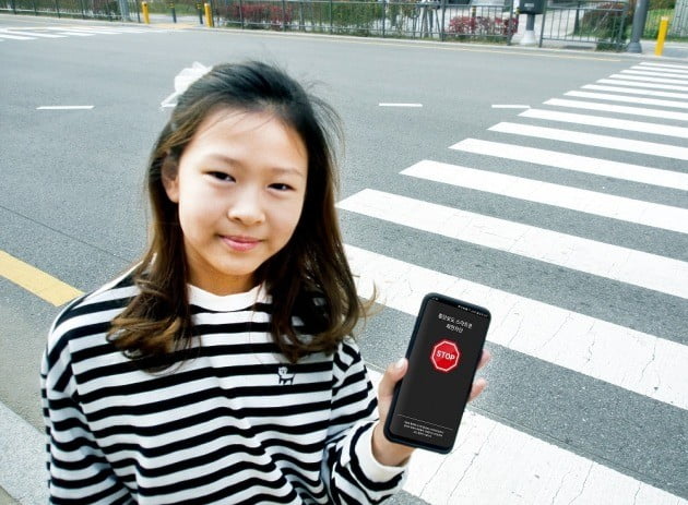한 초등학생이 횡단보도 스마트폰 자동차단 시스템을 적용한 스마트폰을 사용하고 있다. 얍컴퍼니 제공