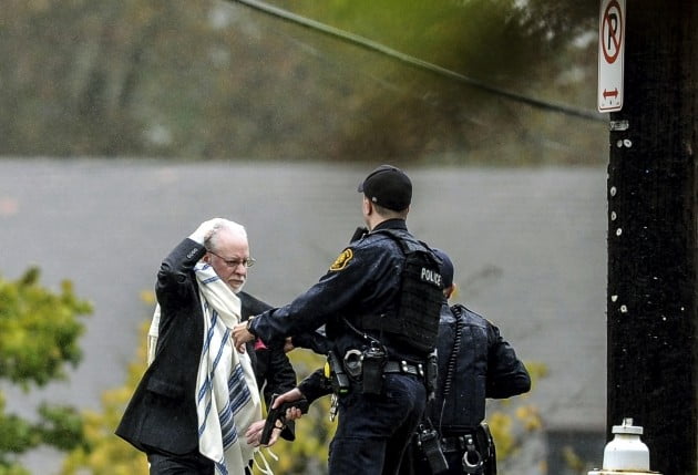 27일(현지시간) 미국 피츠버그 한 유대교 회당에서 총기사건이 발생한 뒤 한 남성이 경찰의 인도를 받고 현장을 빠져나가고 있다. 사진=연합뉴스