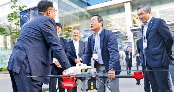 구자열 LS그룹 회장(가운데)과 구자균 LS산전 회장(왼쪽 첫 번째)이 지난달 17일 경기 안양시 LS타워에서 열린 ‘티 페어(T-Fair) 2018’에서 스마트 농업에 사용되는 드론을 함께 들어보고 있다.  /LS 제공 