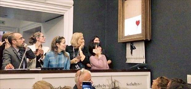 지난 5일 영국 런던 소더비 경매장에서 뱅크시의 작품 ‘풍선과 소녀’가 낙찰되자마자 찢어져 사람들이 놀라워하고 있다.  /한경DB 