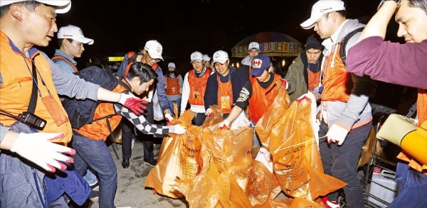 한화그룹 임직원들이 지난 6일 서울 여의도 한강공원에서 열린 서울세계불꽃축제가 끝난 뒤 쓰레기를 치우고 있다.  