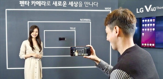한 소비자가 23일 서울 신사동 가로수길 LG V40 씽큐(ThinQ) 체험존에서 ‘트리플 샷’을 찍어보고 있다. 셔터를 한 번 눌러서 망원, 표준, 초광각 후면 3개 렌즈로 각각 사진을 찍어 다양한 화각의 사진을 담을 수 있는 기능이다.  /LG전자 제공 