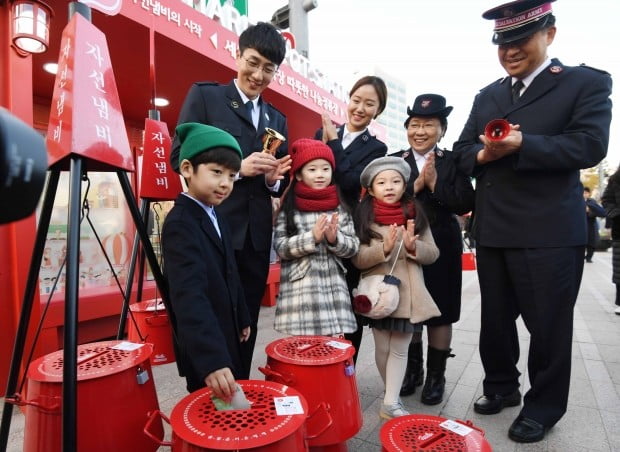 한국구세군이 90주년을 맞아 28일 오전 서울광장에서 휘슬러 코리아와 함께 ‘자선냄비 나눔 정류장 전달식’을 열어 구세군 사관과 어린이들이 성금을 하며 시민들의 참여를 독려하고 있다. 이 정류장은 온실 효과가 있는 벤치 등을 설치해 시민들이 잠시 쉬며 나눔에 참여할 수 있게 했꼬, 12월 한 달간 시청광장에 설치된다./김범준기자bjk07@hankyung.com