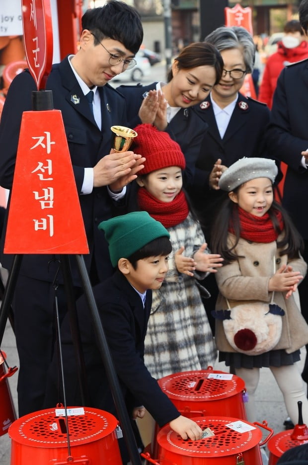 한국구세군이 90주년을 맞아 28일 오전 서울광장에서 휘슬러 코리아와 함께 ‘자선냄비 나눔 정류장 전달식’을 열어 구세군 사관과 어린이들이 성금을 하며 시민들의 참여를 독려하고 있다. 이 정류장은 온실 효과가 있는 벤치 등을 설치해 시민들이 잠시 쉬며 나눔에 참여할 수 있게 했꼬, 12월 한 달간 시청광장에 설치된다./김범준기자bjk07@hankyung.com