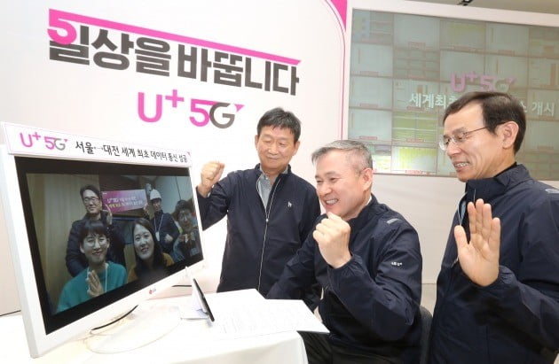  LG유플러스 하현회 부회장(가운데)이 대전기술원에서 서울 마곡 사옥에 5G망으로 걸려온 ‘화상통화’를 직접 받고, 상용 네트워크 서비스의 안정성을 확인하고 있다./사진=LG유플러스