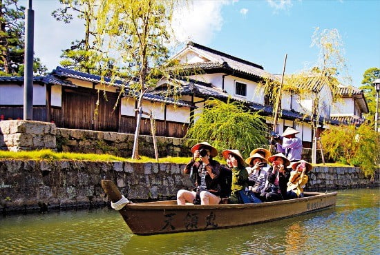거룻배를 타고 일본 전통가옥과 유럽풍 근대건물이 늘어선 구라시키 미관지구를 둘러보는 관광객들. 