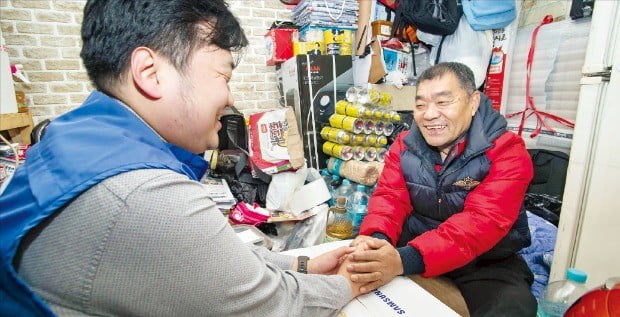 삼성전자 직원이 서울 동대문구에 있는 한 쪽방촌을 찾아 입주 어르신에게 생필품 세트를 전달하고 있다. 삼성전자 제공 