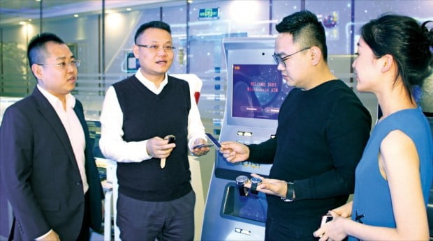 간펑 블록체인연구개발센터 대표(왼쪽 두 번째)가 직원들과 제품 개발에 관해 논의하고 있다. 손에 들고 있는 것이 웨어러블 가상화폐 채굴기, 뒤에 보이는 것은 가상화폐 현금자동입출금기(ATM)다. 