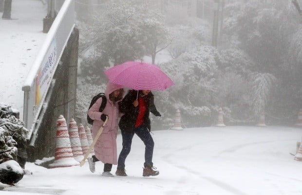 31일 오전 부산 서구 서대신동 꽃마을에서 시민들이 내리는 눈을 맞으며 발걸음을 재촉하고 있다. (사진=연합뉴스)