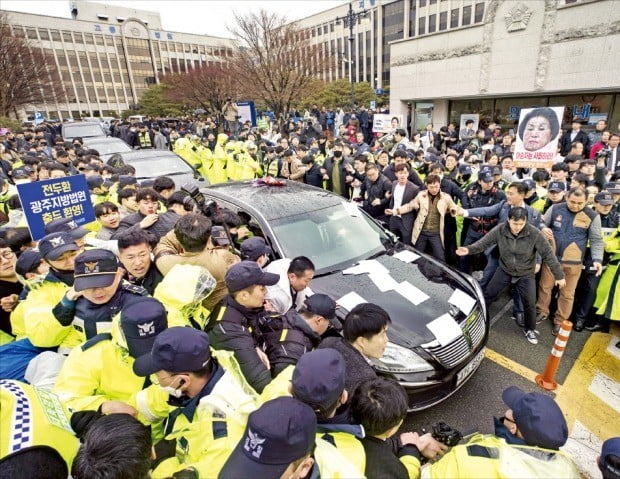 고(故) 조비오 신부의 명예를 훼손한 혐의로 재판에 넘겨진 전두환 전 대통령이 11일 광주지방법원에서 열린 첫 공판에 출석했다. 재판 후 차량(앞에서 두 번째)에 탑승해 서울로 돌아가려 하자 법원 앞에서 기다리고 있던 광주 시민들이 전 전 대통령의 차량 행렬을 막아선 채 분노를 표하고 있다.  /광주=강은구  기자  egkang@hankyung.com