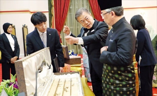 < 말레이 국왕에게 국궁 선물하는 문 대통령 > 문재인 대통령이 13일 저녁 말레이시아 국립 왕궁에서 열린 국빈 만찬에 앞서 압둘라 국왕에게 무용총 수렵도를 새긴 국궁 세트를 선물하면서 활 시위를 당기는 모습을 보여주고 있다.  /연합뉴스 