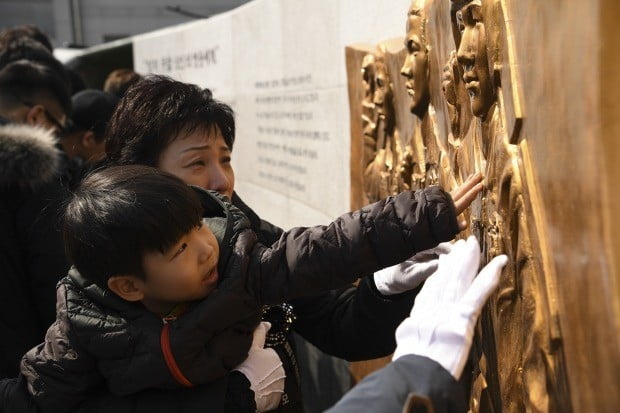 16일 경북 포항 해병대 1사단에서 엄수된 마린온 추락사고 순직 장병 위령탑 제막식에서 유가족이 순직 장병들의 부조상을 어루만지고 있다.사진=해병대사령부 제공