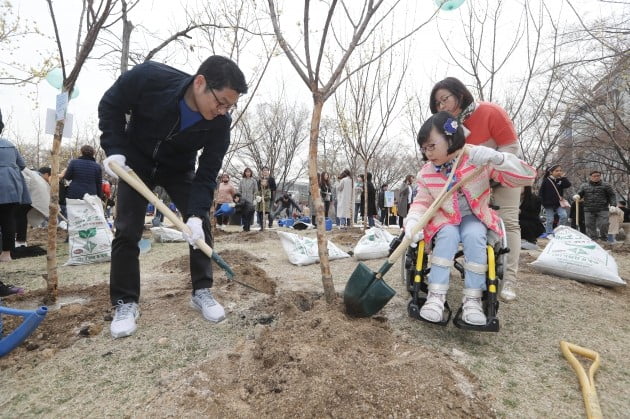 유준원 상상인그룹 대표가 행사에 참가한 휠체어 이용 아동가족과 함께 광화문 경희궁공원에서 이팝나무를 심고있다. 