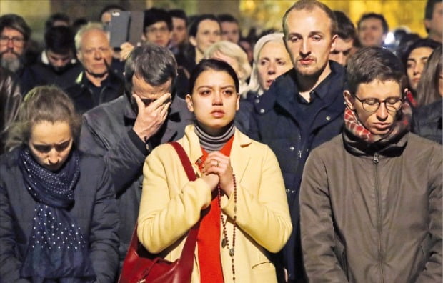 < 눈물 흘리며 “아베마리아~” > 프랑스 파리 시민들과 관광객들이 15일(현지시간) 불길이 휩싸인 파리 노트르담 대성당을 애처롭게 쳐다보고 있다. 시민들이 성가 ‘아베마리아’를 부르며 슬픔에 잠겨 있다.   /AP연합뉴스 