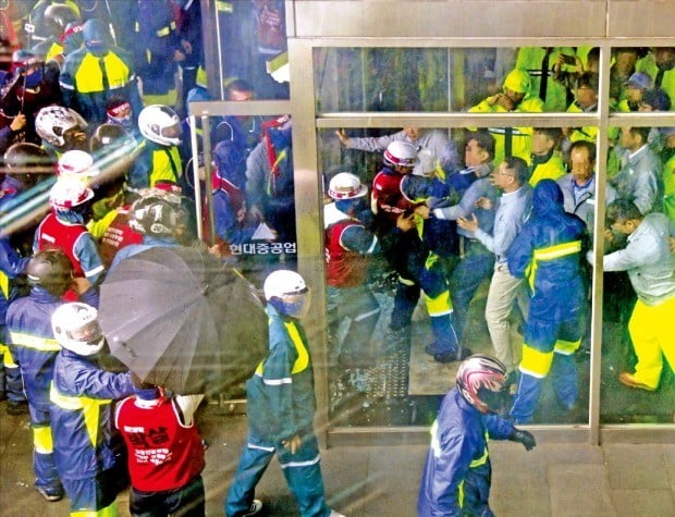 헬멧을 쓴 현대중공업 노조원들이 27일 회사 본관 진입을 시도하자 직원들(오른쪽)이 막고 있다. 이들 간 몸싸움으로 현관 유리문이 깨지고 회사 직원과 노조원 10여 명이 부상당했다.  /현대중공업 제공