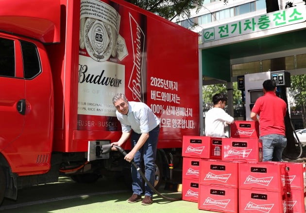 오비맥주 고동우 대표(왼쪽)가 전기차충전소에서 버드와이저 맥주를 운반하는 친환경 전기트럭을 충전하고 있다.